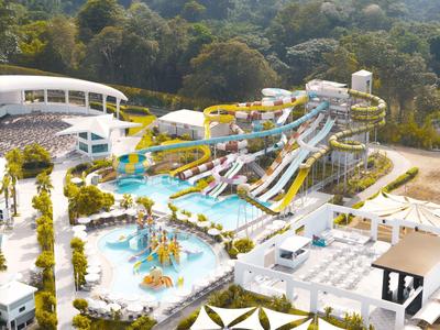 Ein großer Wasserpark mit mehreren Wasserrutschen und einem Kinderbecken in einer grünen Umgebung.