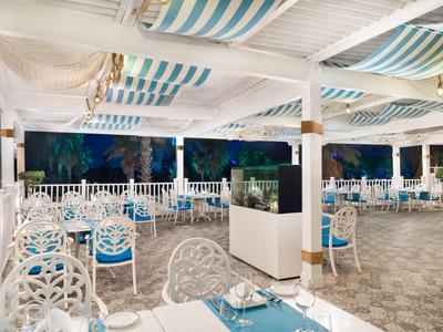 Jasny taras restauracyjny z białymi meblami i niebieskimi akcentami nocą.