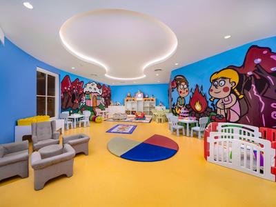 Kolorowy pokój zabaw dla dzieci z malowidłami ściennymi, zabawkami i miejscami do siedzenia w hotelu.