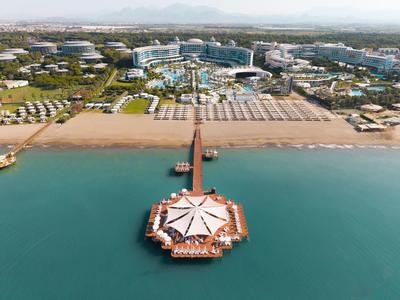 Luksusowy hotel z długim drewnianym pomostem i plażą nad czystą, spokojną wodą.