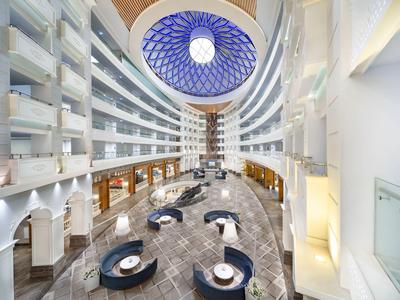 Nowoczesne wnętrze hotelu z okrągłym układem i niebieską dekoracją sufitu.