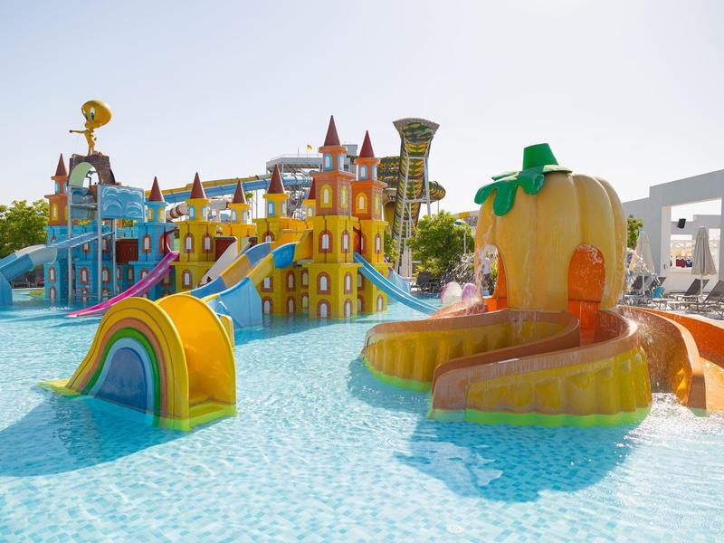 Kolorowy plac zabaw wodny z zjeżdżalniami i atrakcjami w hotelowym basenie.
