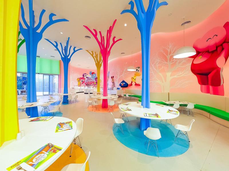 Kolorowy kącik zabaw dla dzieci z żywymi strukturami drzew i nowoczesnymi meblami w jasnym pomieszczeniu.