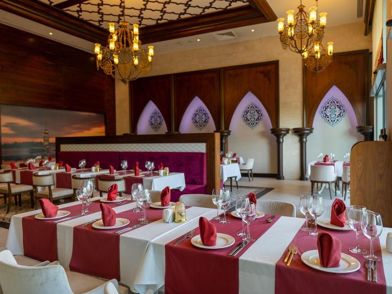 Elegancka restauracja z czerwono-białymi nakryciami stołów i żyrandolami na suficie.