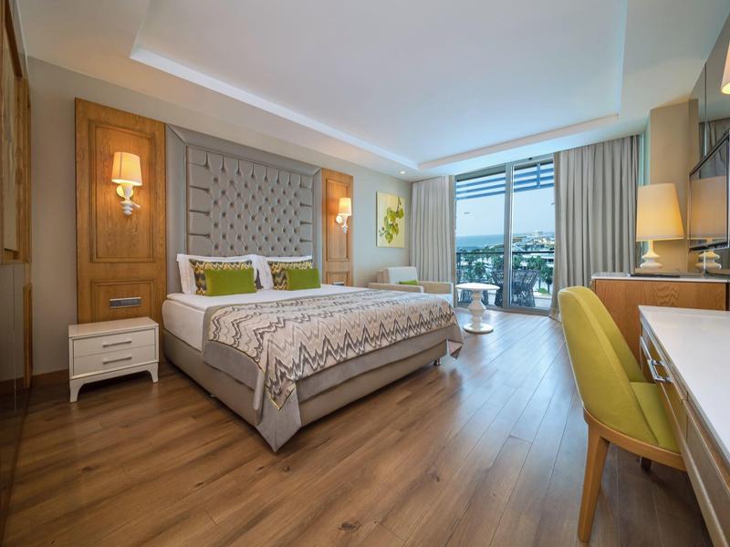 Nowoczesny pokój hotelowy z podwójnym łóżkiem, drewnianą podłogą i miejscem do siedzenia przy oknie.