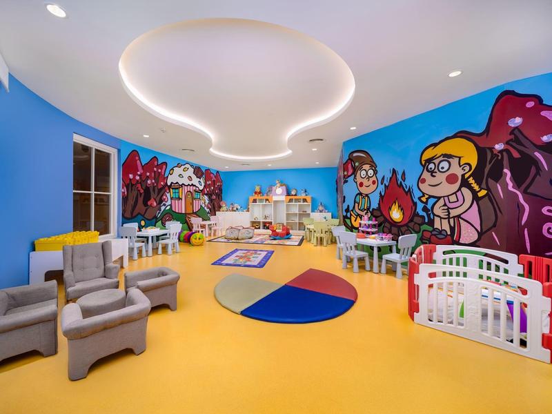 Kolorowy pokój zabaw dla dzieci z malowidłami ściennymi, zabawkami i miejscami do siedzenia w hotelu.