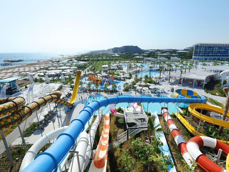 Park wodny z kilkoma kolorowymi zjeżdżalniami i hotelem w tle przy morzu