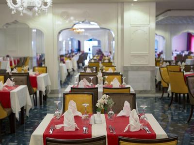 Elegantes Restaurant mit rot gedeckten Tischen, weißen Servietten und bequemen Stühlen in warmen Farben.