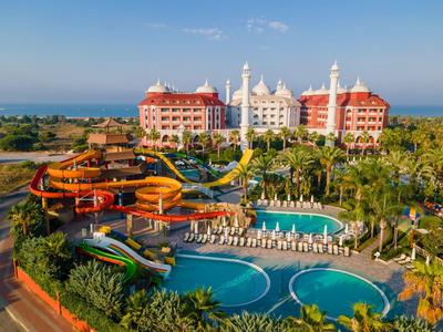 Große Hotelanlage mit Wasserrutschen, mehreren Pools, Palmen und Meerblick im Hintergrund.