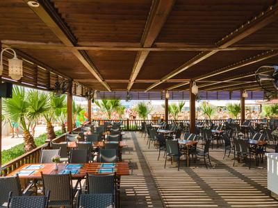 Terrazza coperta con molti tavoli e sedie in un ristorante con vista sulle palme.