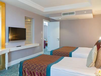 Modernes Hotelzimmer mit zwei Einzelbetten, Flachbildfernseher und heller Wandfarbe.
