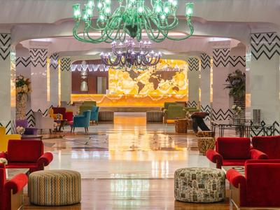 Elegante Hotellobby mit bunten Sesseln, Kronleuchtern und Weltkarte an der Wand.