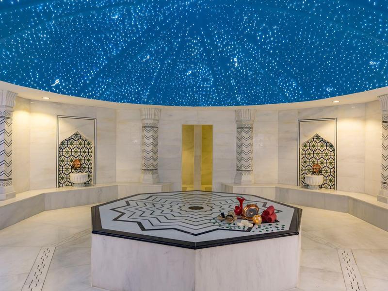 Innenraum eines Hammams mit einem achteckigen Marmorbrunnen und blauer Kuppel