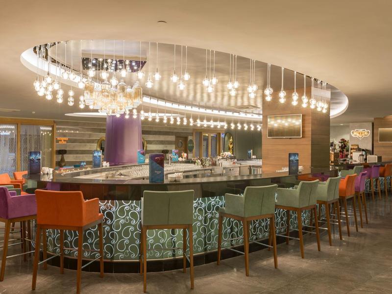 Moderne Bar mit bunten Stühlen und runder Deckenbeleuchtung in einem Hotelrestaurant.