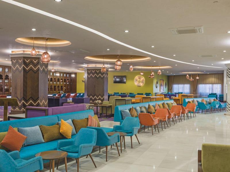 Großer, bunter Hotel-Loungebereich mit modernen Sitzen und dekorativen Säulen.