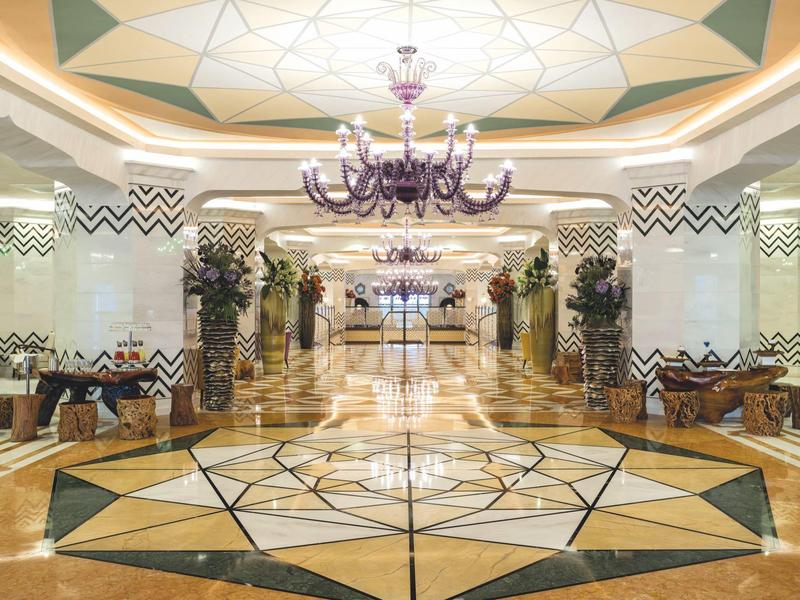 Große, elegant dekorierte Hotellobby mit geometrischem Marmorboden und lila Kronleuchtern