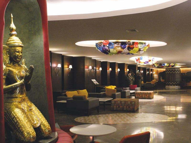 Elegante Hotellobby mit goldenem Buddha, Sitzbereichen und bunten Deckendekorationen