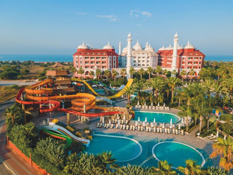 Luxuriöses Resort mit Wasserrutschen, mehreren Pools und Palmen am Meer