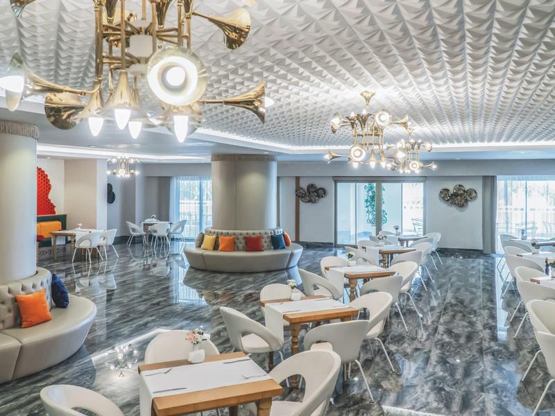 Moderner, heller Hotel-Loungebereich mit stilvollen Sitzgelegenheiten und dekorativen Deckenleuchten.