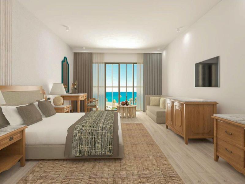 Habitación de hotel luminosa con vista al mar, dos camas y muebles de madera de diseño natural.