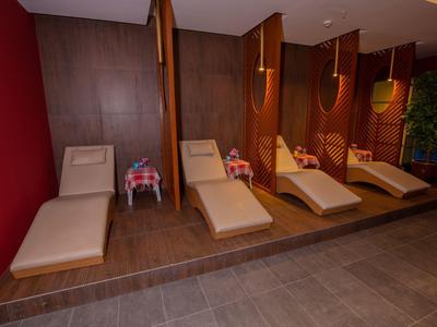 Quattro lettini moderni davanti a pareti in legno in un'area benessere tranquilla.