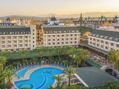 Kompleks hotelowy z basenem i ogrodem na tle miejskiego krajobrazu o zachodzie słońca