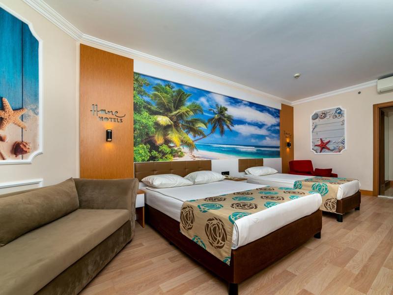 Camera d'hotel con due letti singoli, divano e decorazioni murali a tema spiaggia