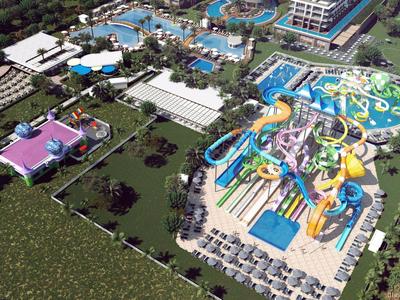Vista aérea de un parque acuático con varias piscinas, toboganes de agua y tumbonas junto a edificios hoteleros.
