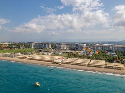 Vista di una lunga spiaggia sabbiosa con hotel e città sullo sfondo sotto un cielo nuvoloso.