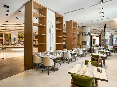 Ampia zona ristorante moderna dell'hotel con divisori in legno, sedie bianche e tavoli apparecchiati.