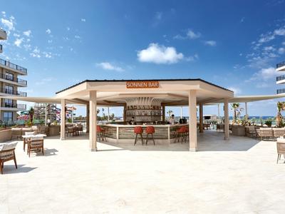 Area bar da spiaggia aperta con sedie sotto un cielo limpido in un resort.