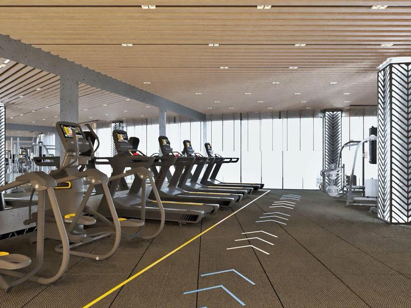 Gimnasio moderno con cintas de correr, equipos de cardio y techo de madera clara en un hotel.