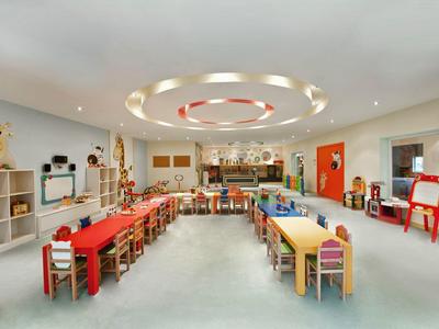 Großer, heller Kinderspielraum mit bunten Tischen, Stühlen und Spielzeug