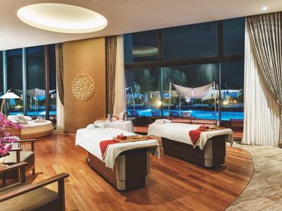 Eleganter Wellnessraum mit Massagebetten und Blick auf Stadtlichter bei Nacht.