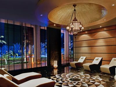 Modernes Hotelzimmer mit großen Fenstern und Blick auf tropische Pflanzen bei Nacht