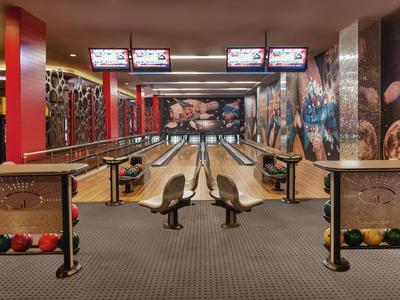 Moderna pista da bowling con schermi illuminati e pareti colorate in un'area ricreativa.