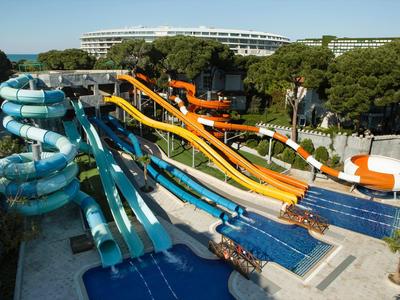 Mehrere bunte Wasserrutschen münden in mehrere Pools in einem Hotelwasserpark