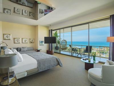 Modernes Hotelzimmer mit großem Bett und Meerblick durch bodentiefe Fenster