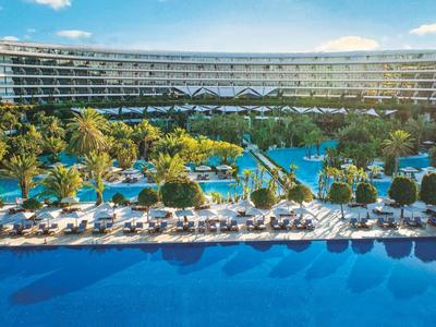 Großes Resort mit weitläufigem Pool, Sonnenliegen und Palmen unter blauem Himmel.