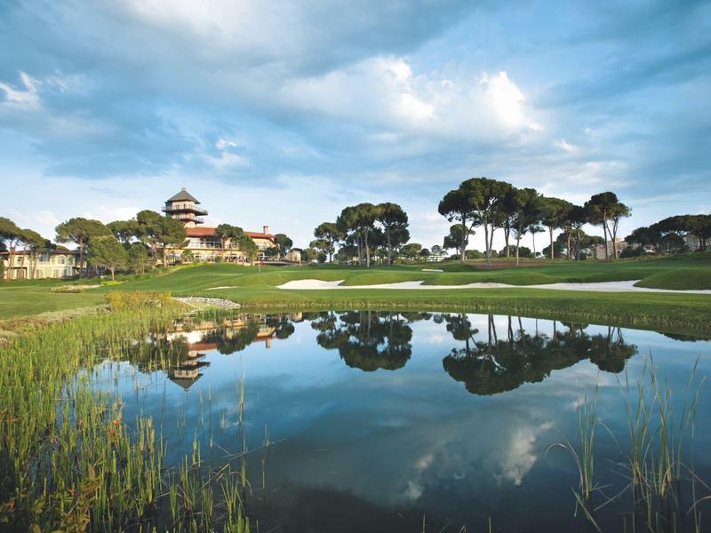 Golfplatz mit Teich und Bäumen unter blauem Himmel