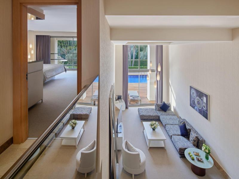 Moderner Wohnbereich mit weißem Mobiliar und Blick auf einen Außenpool.