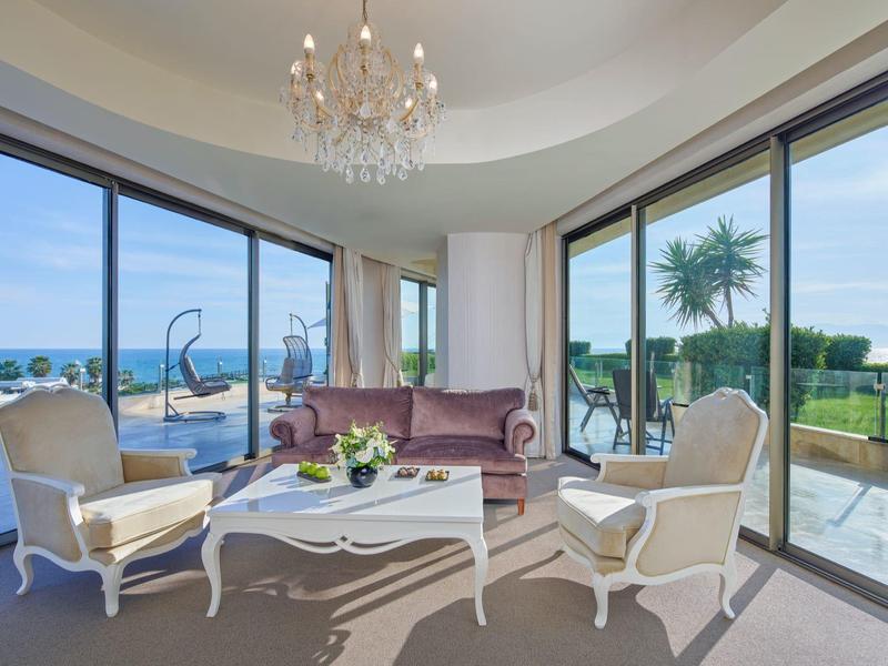 Elegantes Wohnzimmer mit Blick auf den Ozean, zwei Sesseln, Sofa und Kronleuchter