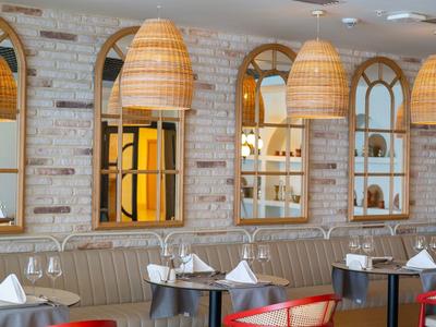 Moderne Hotellounge mit roten Stühlen, runden Tischen und warmen Hängeleuchten.