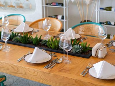 Eleganter Esstisch im Restaurant mit weißen Servietten, Weingläsern und grüner Dekoration.