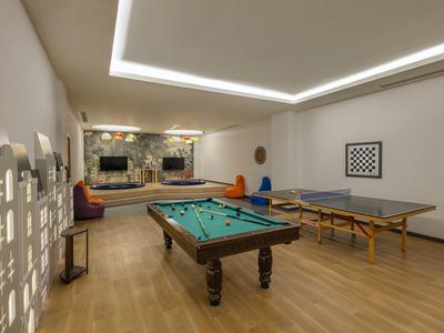 Großer heller Raum mit Billardtisch, Tischtennisplatte, Holzfußboden und moderner Deckenbeleuchtung.