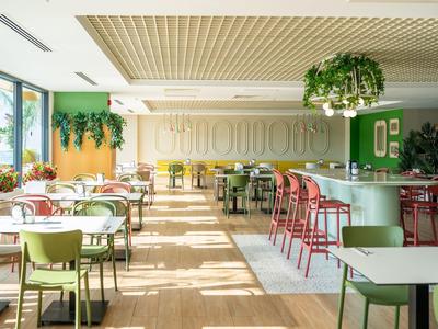 Helles, modernes Restaurant mit grünen und roten Stühlen, Pflanzen und Tageslicht im Hotel.