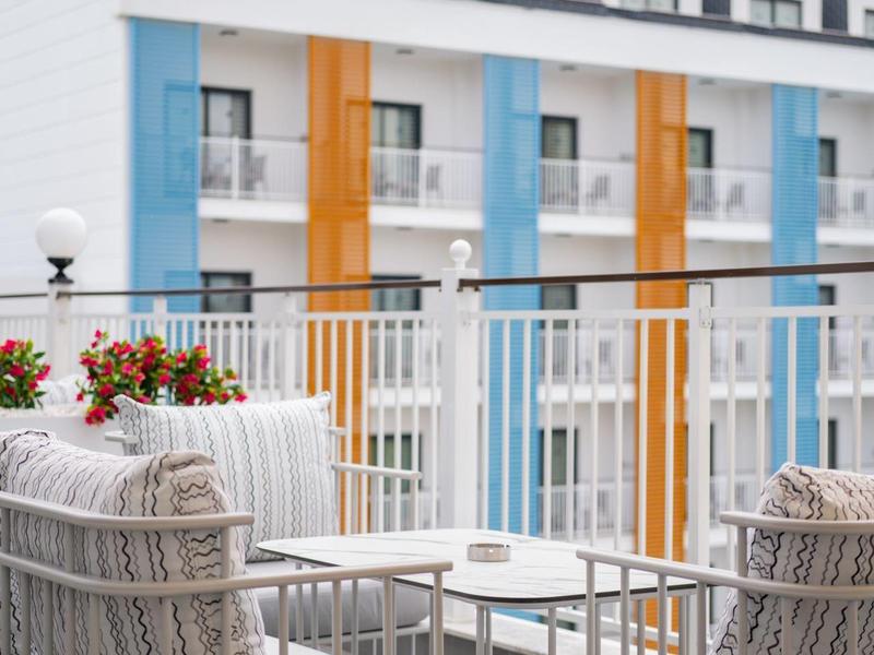 Moderne balkonterras met comfortabele stoelen en kleurrijke hotelbalkons op de achtergrond