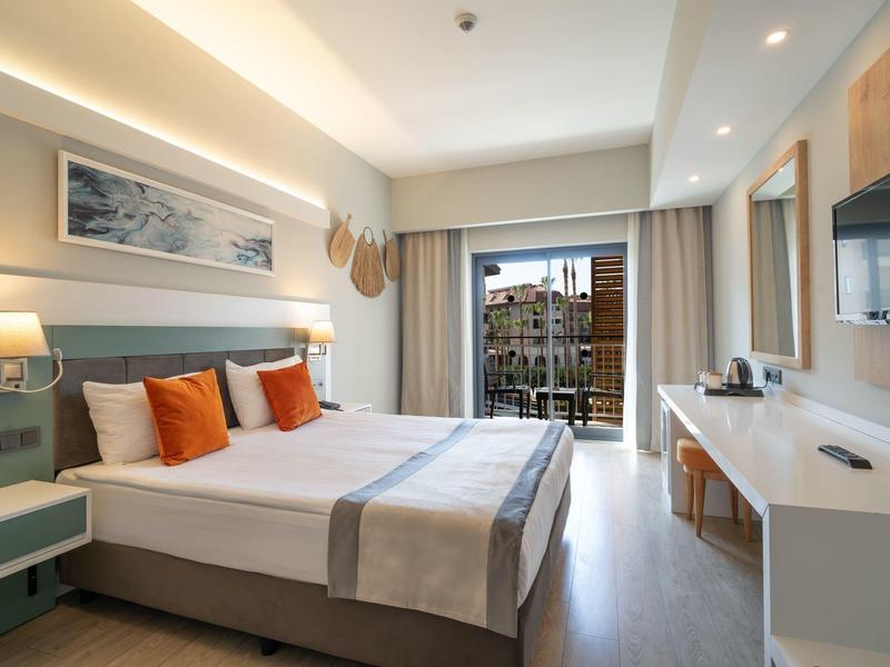 Modern ingerichte hotelkamer met tweepersoonsbed, balkon en bureau