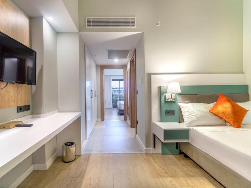 Moderne hotelkamer met tweepersoonsbed, tv en minimalistisch ontwerp.