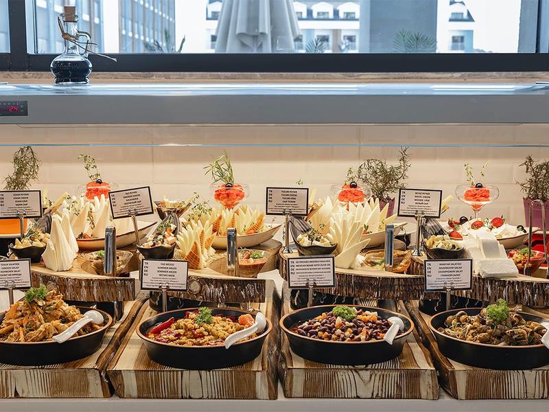 Buffet met verschillende warme gerechten gerangschikt in pannen op een houten tafel